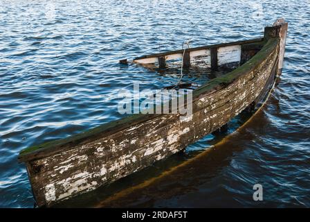 A sunken ship wreck rests at the bottom of a peaceful harbor, its hull shimmering in the sunlit sea. Stock Photo