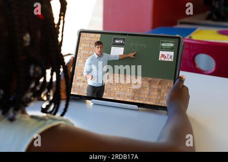 African american girl looking at male teacher explaining to her through video call on laptop Stock Photo