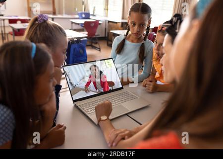 Multiracial teacher and students video calling over laptop while studying online in classroom Stock Photo