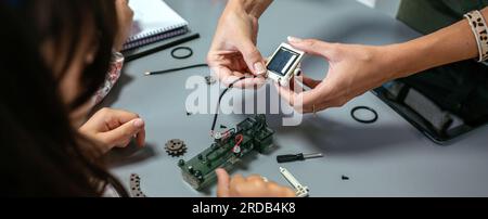 Female teacher explaining to student how connect a solar panel on electrical circuit Stock Photo