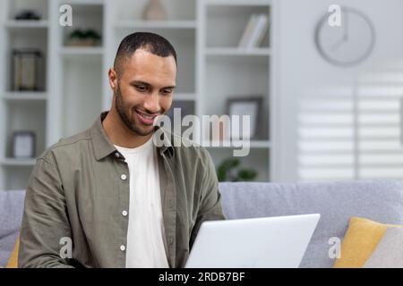 Portrait of young smiling African American male student studying remotely at home with laptop. Close-up photo. Stock Photo