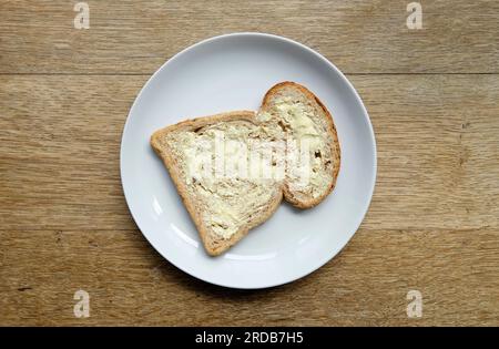 slice of buttered bread on white plate Stock Photo