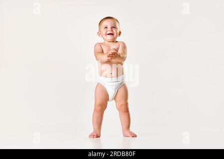 Portrait of little boy, baby, child in diaper standing near wall isolated  over white studio background. Childhood concept Stock Photo