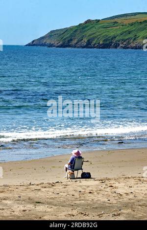 Life's a beach. A solitary lady just sitting on Aberdaron beach and enjoying the view Stock Photo