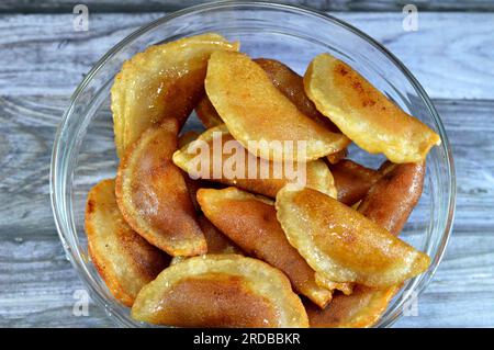 A bowl of qatayef dumplings stuffed and filled with nuts and shredded coconut fried in deep oil and soaked with sugar syrup, Arabic dessert folded pan Stock Photo