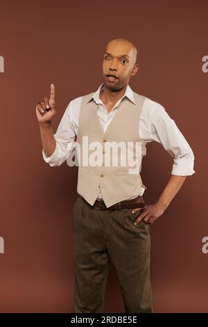 inclusion, myasthenia gravis syndrome, bold african american man standing with hand on hip and pointing up, looking at camera, dark skinned, real peop Stock Photo