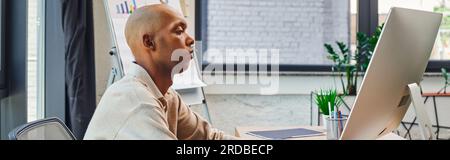 inclusion, african american man with myasthenia gravis at work, bold and dark skinned office worker using computer, looking at monitor, graphs and fli Stock Photo