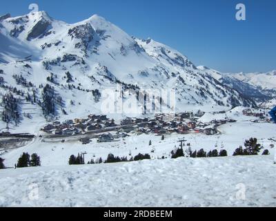 View from the ski slope to the valley of Obertauern with all its hotels and restaurants covered with snow and surrounded by white mountains Stock Photo