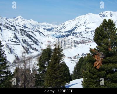 View from the ski slope to the valley of Obertauern with all its hotels and restaurants covered with snow and surrounded by white mountains Stock Photo