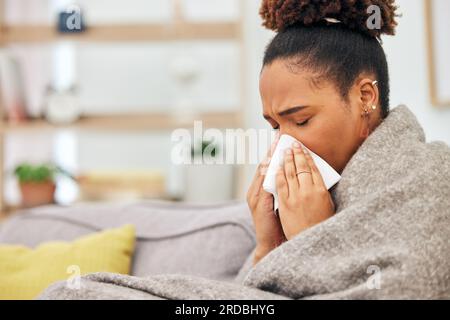 Sick, woman and blowing nose with blanket in home from hayfever allergies, cold and winter virus. Face, tissue and black female person sneeze from Stock Photo