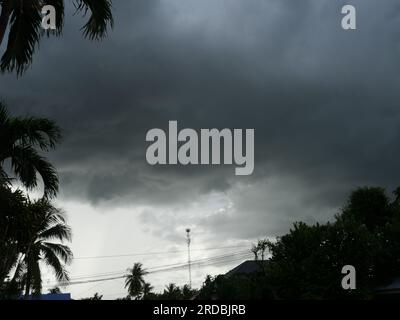 Trees and Mobile phone antenna tower silhouette with Cumulonimbus cloud formations on tropical sky , Nimbus moving Stock Photo