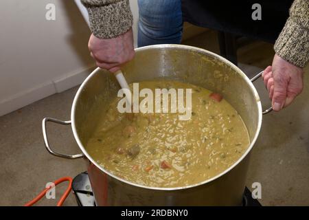 Stirring in a large pan filled with Dutch pea soup. Stock Photo