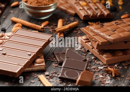 Whole and broken chocolate, chocolate bars, candies, chocolate chips on a dark wooden background Stock Photo