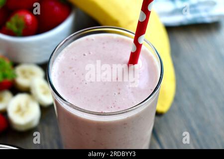 Strawberry banana smoothie in a clear glass on a wooden table Stock Photo