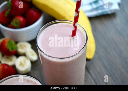 Strawberry banana smoothie in a clear glass on a wooden table Stock Photo