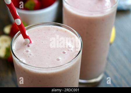 Strawberry banana smoothie in a clear glass on a wooden table Stock Photo