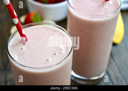 Strawberry banana smoothie in a clear glass on a wooden table Stock Photo