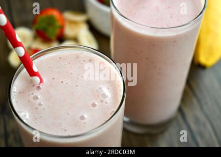 Strawberry banana smoothie in a clear glass on a wooden table Stock Photo