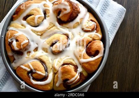 Cinnamon rolls in a round baking pan on a rustic wooden table Stock Photo