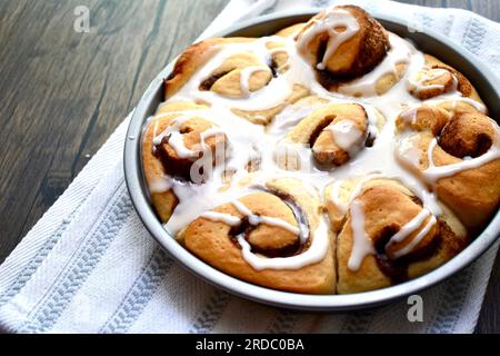 Cinnamon rolls in a round baking pan on a rustic wooden table Stock Photo