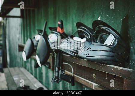 Paintball, helmet and guns on rack at station of sports gear waiting for match, competition or war battle. Paint balling sportswear, weapon or safe Stock Photo