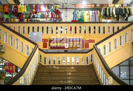 The stylish yellow-painted main staircase leading to clothing stalls on the upper floor inside Hoi An Market, in central Vietnam. Stock Photo