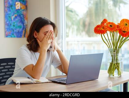 Mad young woman worker losing job result on broken pc, low internet connection, working remotely at home. Stressed attractive lady annoyed by hard work task or system crash. Stock Photo