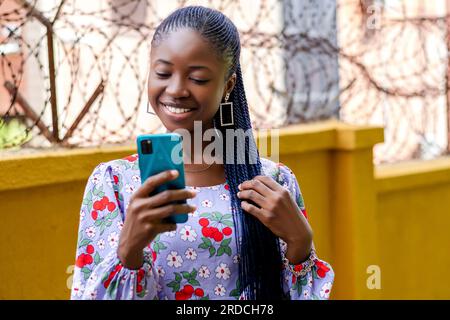 Photo of a joyful African woman smiling while using her cell phone Stock Photo