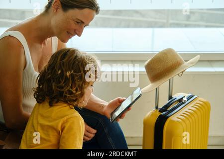 Mother and son using smartphone in airport Stock Photo