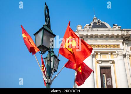 The communist hammer and sickle and Vietnamese gold-starred flags fly from a lamppost outside the Hanoi Opera House, in Hanoi, Vietnam Stock Photo