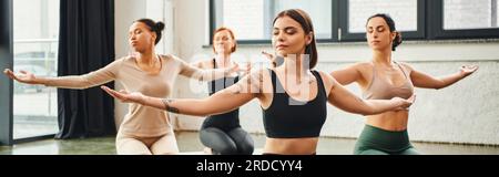 diverse multicultural female friends in sportswear practicing yoga and meditating with closed eyes and outstretched hands, inner peace and body awaren Stock Photo