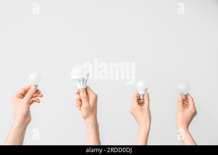Electrician hands with light bulbs on grey background Stock Photo