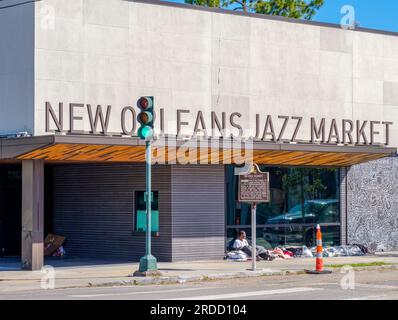 NEW ORLEANS, LA, USA - FEBRUARY 5, 2023: Homeless man and The New Orleans Jazz Market on Oretha Castle Haley Boulevard in Central City Stock Photo