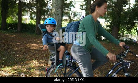 Child sitting in bicycle back seat chair with mother riding bike Stock ...