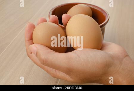 Quality brown eggs, highlighted in the bowl on the table, to ensure a tasty meal. Stock Photo
