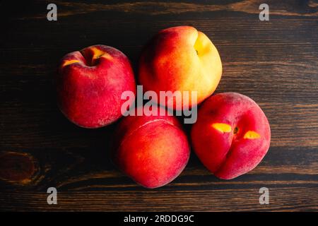 Group of Four Peaches on a Wooden Background: Fresh peaches grouped on a dark wood background Stock Photo