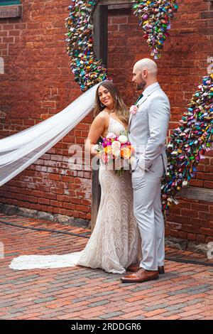 Newly wed couple posing for photographs by a heartshaped installation of Love Locks in the historic Distillery district of Toronto Ontario Canada Stock Photo