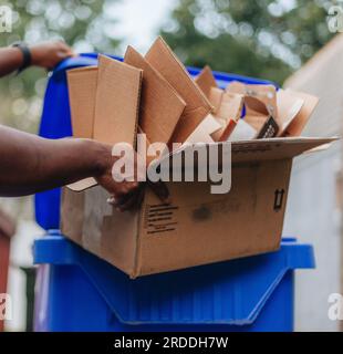 African American man putting cardboard into recycle bin Stock Photo - Alamy