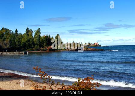 Wooden pier fronts image; rustic and weathered on Lake Superior, Michigan.  Background shows Eagle Harbor Lighthouse and Keweenaw Peninsula. Stock Photo