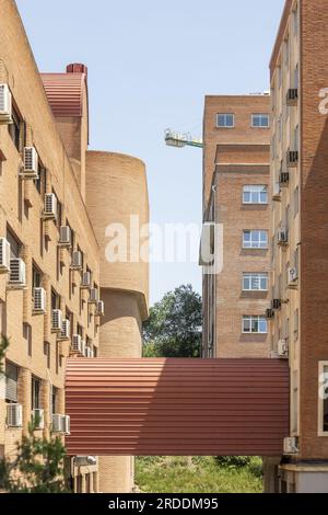 Buildings with brick facades with a covered walkway between them and many individual air conditioners Stock Photo