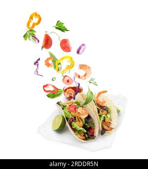 Delicious tacos. Ingredients falling into tortillas on white background Stock Photo