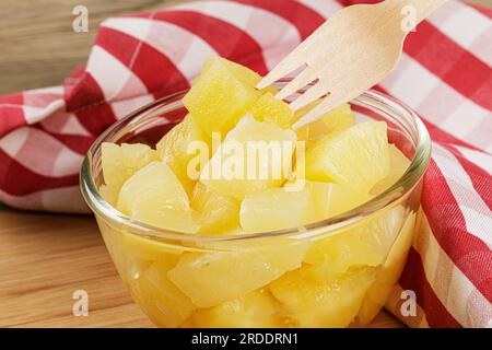 A close up of delicious Pineapple Chunks is juicy Syrup on a wooden background with copy space Stock Photo