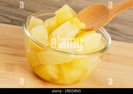 A close up of delicious Pineapple Chunks is juicy Syrup on a wooden background with copy space Stock Photo