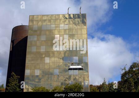 Office building in Hancock, Michigan gets its regular window cleaning.  Two workers are suspended on scaffolding working to clean the salt spray from Stock Photo