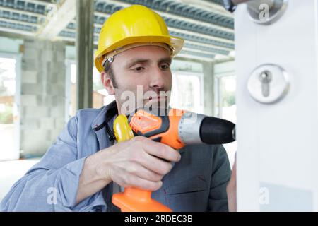 workman using cordless screwdriver on door lock Stock Photo