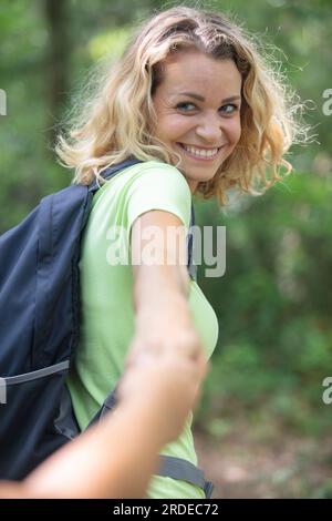 hiker woman holding mans hand in nature Stock Photo