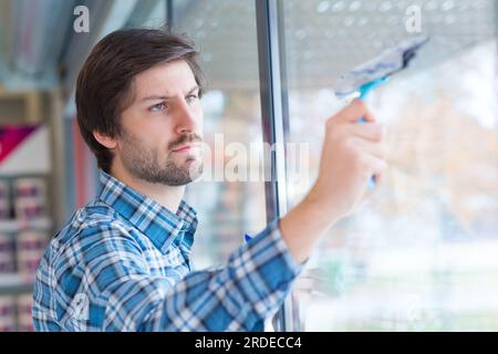 man removing dirt on the glass window using a squeegee Stock Photo