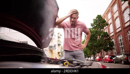 Broken Down Car. Frustrated Man Looking At Smoke Stock Photo