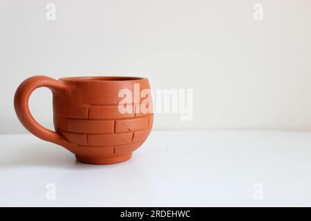 Tea cup made of red soil placed isolated. brick style pattern on the outer side of the cup with the handle to hand the cup. organic and natural Stock Photo