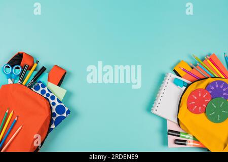 Back to school, education, learning concept. Two open backpacks with school supplies on pastel blue background. Top view Stock Photo